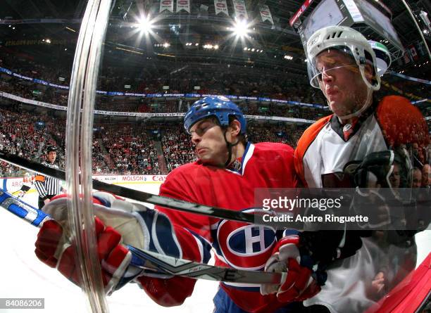 Tom Kostopoulos of the Montreal Canadiens bodychecks Ossi Vaananen of the Philadelphia Flyers into the glass at the Bell Centre on December 18, 2008...