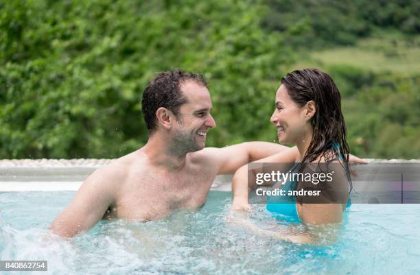happy couple in the swimming pool enjoying their summer holidays - happy holidays around the world stock pictures, royalty-free photos & images