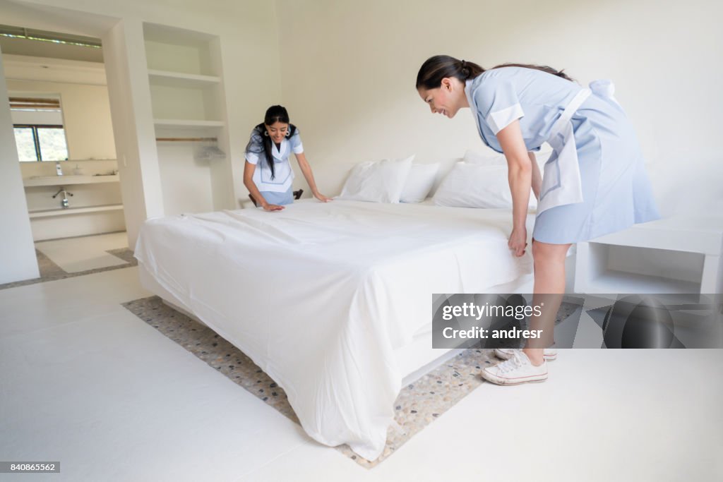 Happy housekeepers making the beds at a hotel