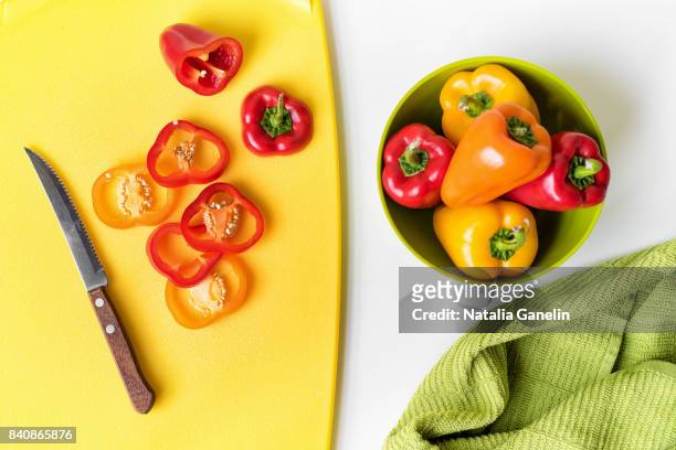 sweet bell peppers in bowl and on cutting board - bell pepper stockfoto's en -beelden