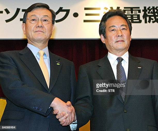 Japan's electronics giant Panasonic president Fumio Otsubo shakes hands with Sanyo president Seiichiro Sano at a press conference in Osaka, western...