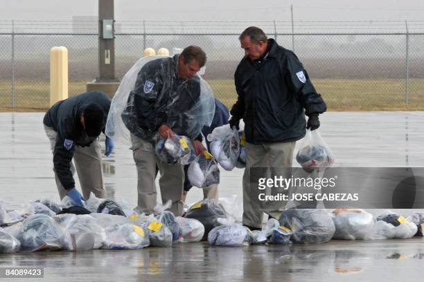 Security officers search the plastic bags containing the personal belongings of Salvadorean illegal immigrants before letting them board the plane to...