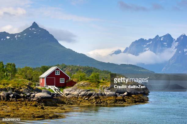 shoreline of raftsund strait with red-painted house and trolltinden mountain range, lofoten islands, nordland, norway - lofoten bildbanksfoton och bilder