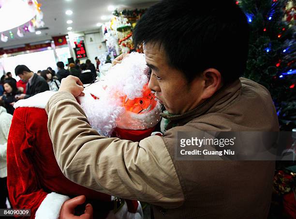Chinese worker of a Christmas decorations store installs models of Santa Claus at a market on December 19, 2008 in Beijing, China. A large number of...