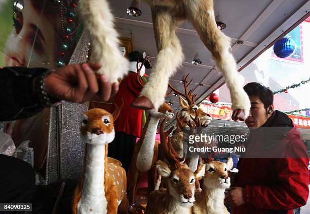 Chinese workers from a Christmas decorations store display their products at a market on December 19, 2008 in Beijing, China. A large number of...