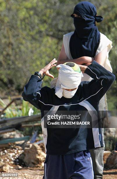 Israeli settlers tie masks around their faces near the Jewish settlement of Kharsina, north of the occupied West Bank city of Hebron, on October 31,...