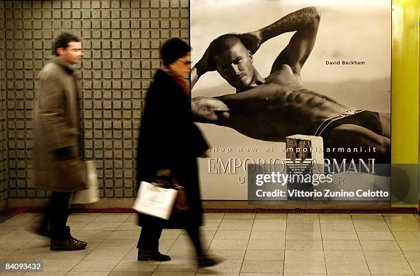 People walking in the underground pass a poster featuring David Beckham modeling underwear in the latest Emporio Armani campaign on December 19, 2008...