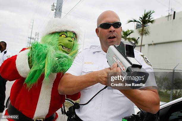 Monroe County Sheriff's Lieutenant Lou Caputo, dressed as the Grinch, helps Monroe County Sheriff deputy Wilfredo Guerra with the laser gun as they...