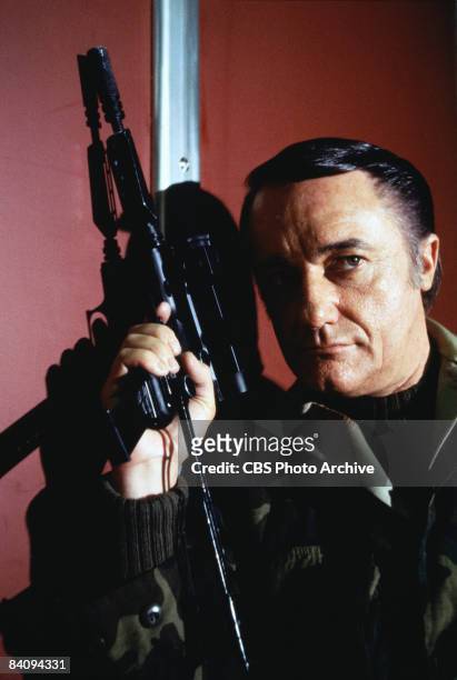 Robert Vaughn carries a sub-machine gun as Napoleon Solo from the television spy series 'The Man From U.N.C.L.E., 1983. United States.
