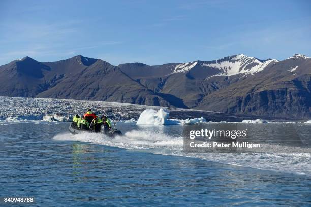 rigid inflatable boat speeds towards a glacier cliff face at jökulsárlón, iceland - breidamerkurjokull glacier stock pictures, royalty-free photos & images
