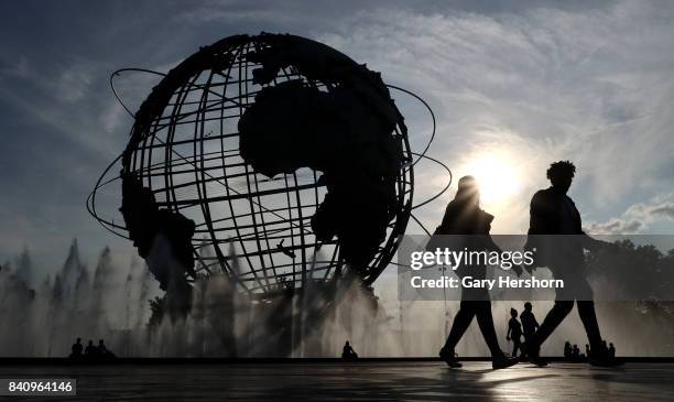 People walk past the Unisphere, a spherical stainless steel representation of the Earth built for the 1964 World's Fair in Flushing Meadows Corona...