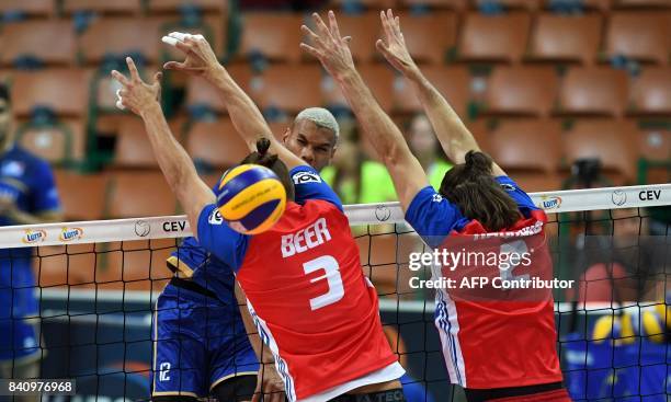 Stephen Boyer of France spikes the ball against Marek Beer and Jan Hadrava of the Czech Republic during the playoff phase match between France and...