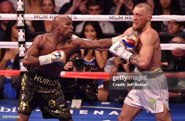 Floyd Mayweather Jr. Punches Conor McGregor in their super welterweight boxing match at T-Mobile Arena on August 26, 2017 in Las Vegas, Nevada....