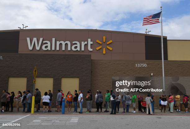 People wait in line for a Walmart store to open after Hurricane Harvey caused heavy flooding in Houston, Texas on August 30, 2017. Monster storm...