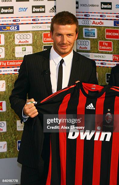 David Beckham holds an AC Milan shirt as he poses for photographers after a press conference at the San Siro Stadium where he signed for AC Milan on...