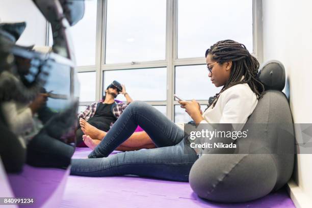 young businesswoman using mobile phone during break in creative office - bean bag stock pictures, royalty-free photos & images