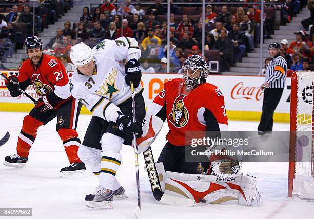 Martin Gerber of the Ottawa Senators makes a pad save down low with Mark Parrish of the Dallas Stars planted at the top of the crease trying to get...