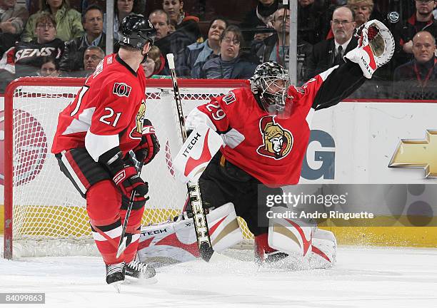 Martin Gerber of the Ottawa Senators reaches to make a glove save against the Dallas Stars as Jason Smith of the Ottawa Senators looks on at...