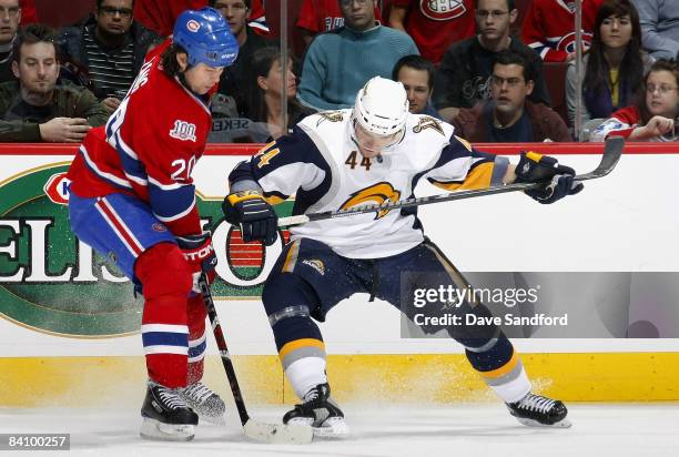 Andrej Sekera of the Buffalo Sabres battles for the puck with Robert Lang of the Montreal Canadiens during their NHL game at the Bell Centre December...