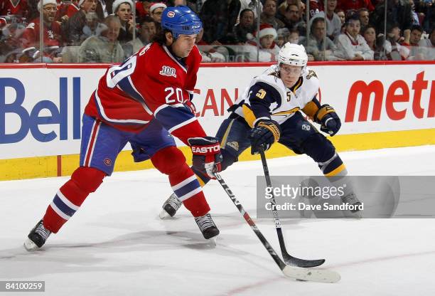 Toni Lydman of the Buffalo Sabres battles for the puck with Robert Lang of the Montreal Canadiens during their NHL game at the Bell Centre December...