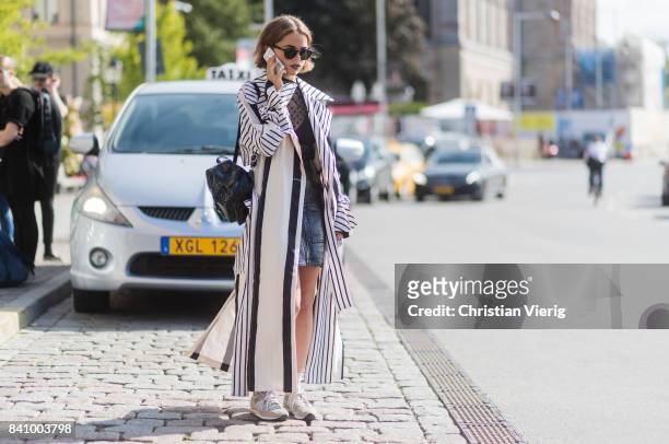 Guest wearing as striped coat outside Whyred on August 30, 2017 in Stockholm, Sweden.