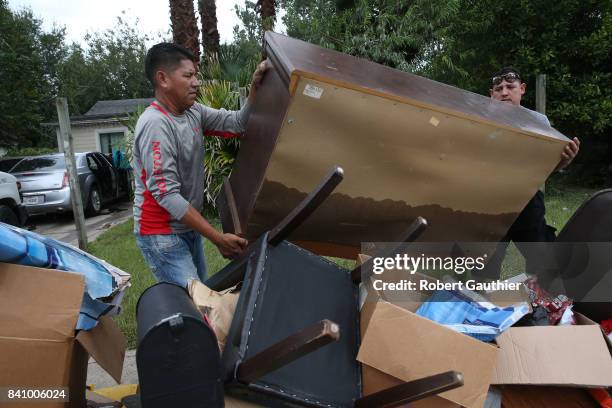 Rafael Minor, left, and Miguel Ramirez remove the contents of Maria Salazar's Northeast Houston home as residents begin rebuilding from the...