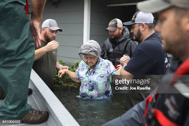 Volunteer rescuer workers help a woman from her home that was inundated with the flooding of Hurricane Harvey on August 30, 2017 in Port Arthur,...