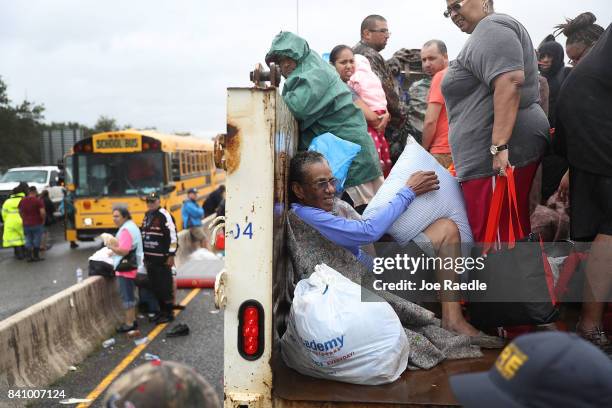 Evacuees ride on a truck after they were driven from their homes by the flooding from Hurricane Harvey on August 30, 2017 in Port Arthur, Texas....