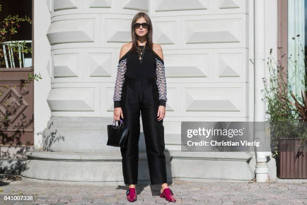 Darja Barannik wearing off shoulder top, black pants, red slippers outside Stylein on August 30, 2017 in Stockholm, Sweden.