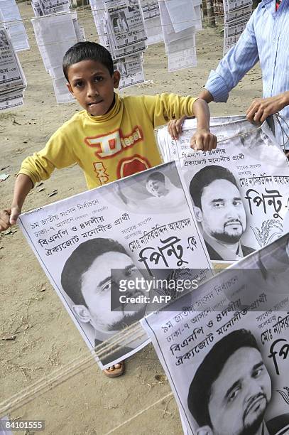 Bangladeshi child assists as others prepare election campaign material in old Dhaka on December 21, 2008. A general election is scheduled to be held...