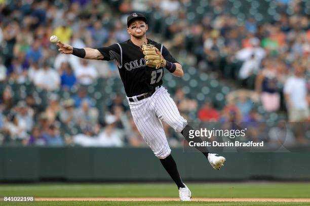 Trevor Story of the Colorado Rockies throws to first base for an out while blowing a bubble gum bubble in the sixth inning of a game against the...