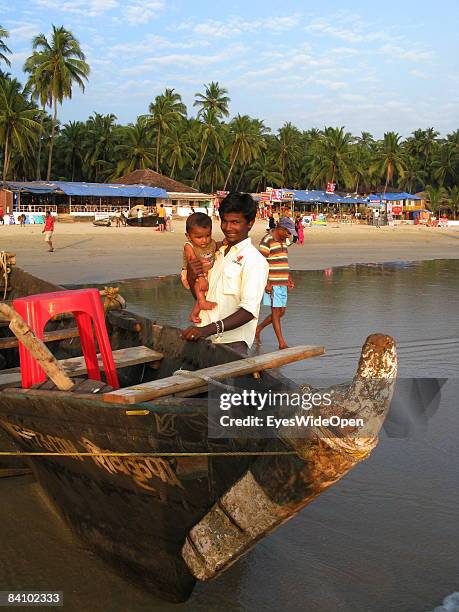 Young indian Fisherman with his baby on the fine sandy beach Palolem on January 08, 2008 in Goa, India.