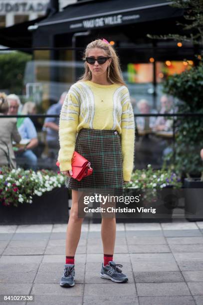 Emili Sindlev wearing a yellow sweater, skirt red JW Anderson bag outside Rodebjer on August 30, 2017 in Stockholm, Sweden.