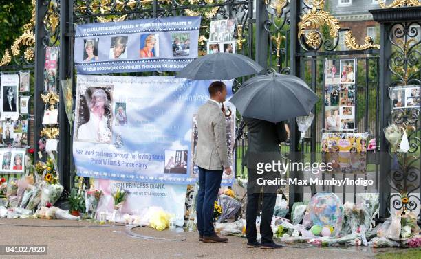 Prince William, Duke of Cambridge and Prince Harry view tributes to Diana, Princess of Wales left at the gates of Kensington Palace after visiting...