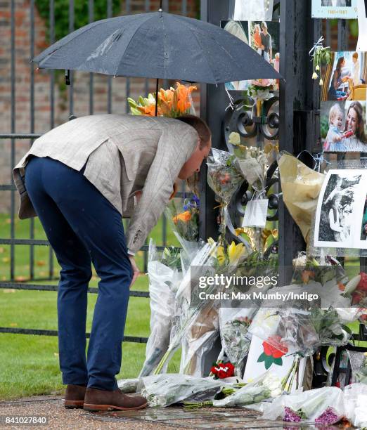 Prince William, Duke of Cambridge views tributes to Diana, Princess of Wales left at the gates of Kensington Palace after visiting the Sunken Garden...