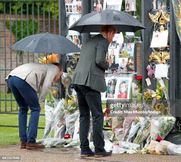 Prince William, Duke of Cambridge and Prince Harry view tributes to Diana, Princess of Wales left at the gates of Kensington Palace after visiting...