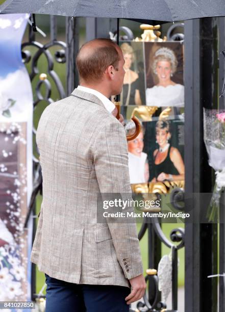 Prince William, Duke of Cambridge views tributes to Diana, Princess of Wales left at the gates of Kensington Palace after visiting the Sunken Garden...