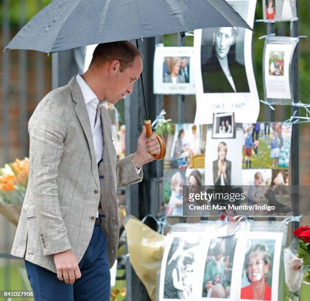 Prince William, Duke of Cambridge views tributes to Diana, Princess of Wales left at the gates of Kensington Palace after visiting the Sunken Garden...