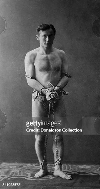 Harry Houdini, full-length portrait, standing, facing front, in chains in circa 1900.