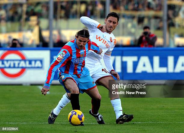 Ezquiel Carboni of Catania competes with Francesco Totti of Roma during the Serie A match between Catania and Roma at the Stadio Massimino on...