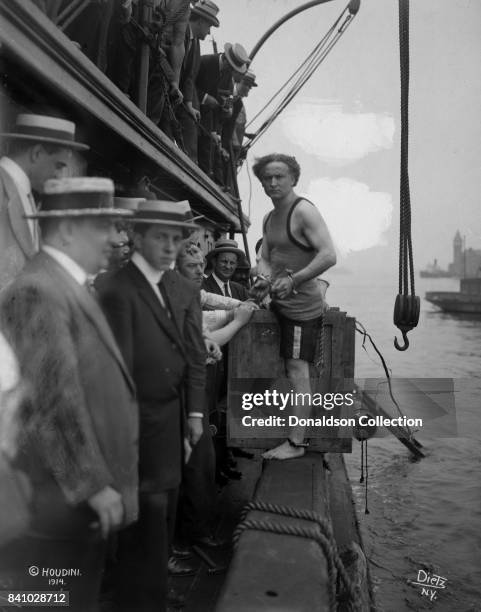 Houdini getting to a packing case, is lowered into New York Bay in 1914.