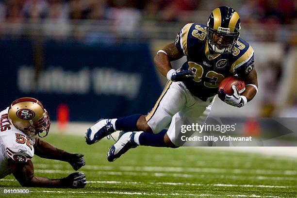 Kenneth Darby of the St. Louis Rams is tripped up by Patrick Willis of the San Francisco 49ers at the Edward Jones Dome on December 21, 2008 in St....