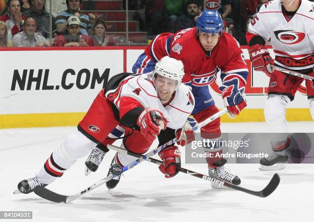 Dennis Seidenberg of the Carolina Hurricanes reaches for a loose puck as he is tripped up by Tom Kostopoulos of the Montreal Canadiens at the Bell...