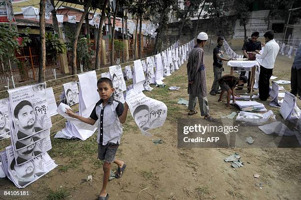 Bangladeshi child carries a poster as political supporter prepare election campaign material in old Dhaka on December 21, 2008. A general election is...