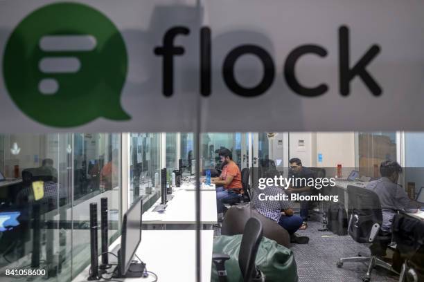 Signage for Flock is displayed on a glass wall as employees work at the company's office in Mumbai, India, on Wednesday, June 28, 2017. Flock, a...