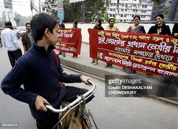 Young Bangladeshi cyclist stops to read a banner held by activists demanding a live telecast debate between the country's two major Political...