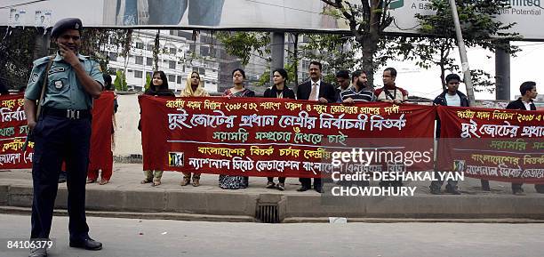 Bangladeshi looks on as he stands beside a banner held by activists demanding a live telecast debate between the country's two major Political...