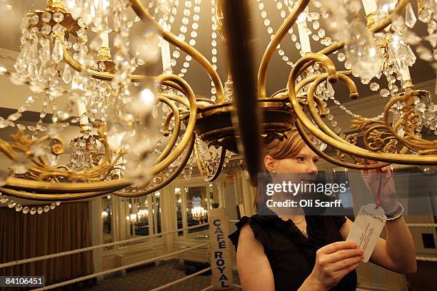 Gallery assistant for Bonhams auctioneers adjusts the guide price tag on a chandelier at the Cafe Royal on Regent Street on December 22, 2008 in...