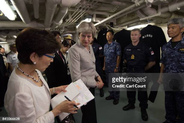 Britain's Prime Minister, Theresa May, listens to an interpreter as she meets British and Japanese naval personnel on board the Japanese navy's...