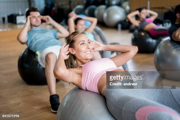 persone in palestra in una lezione di ginnastica usando palle fitness - sit up foto e immagini stock